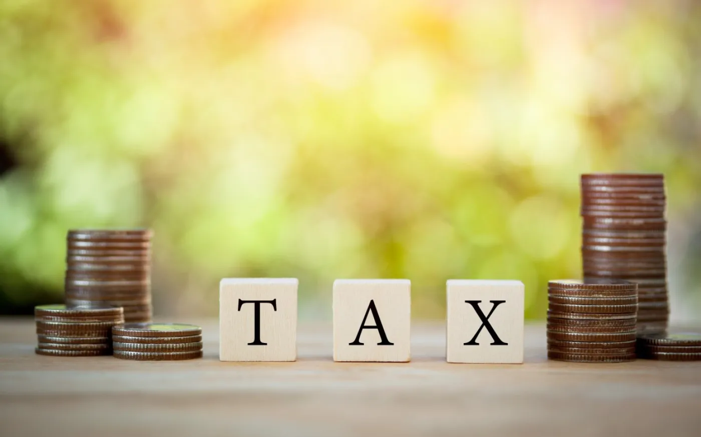 Wooden block on stack coins to show TAX concept