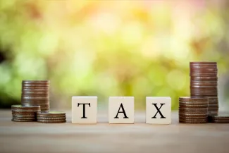 Wooden block on stack coins to show TAX concept